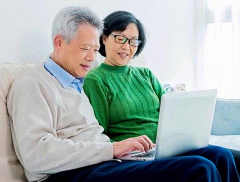Asian Couple Reading on Laptop Together